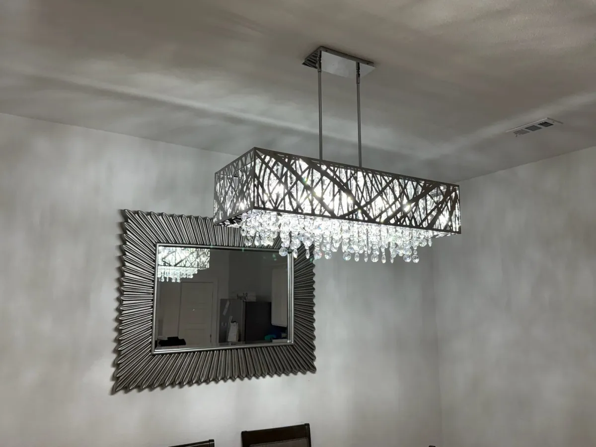 Installed rectangular crystal chandelier hanging from a ceiling above a dining area