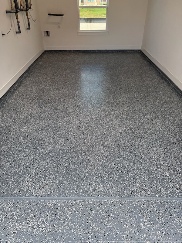 Gray flake epoxy-style garage floor finish in a clean residential garage room